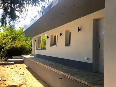 Hosszú, fedett bejárati terasz a fehér és antracit homlokzat mellett